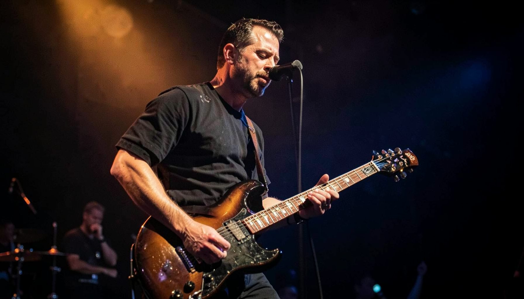 Rock guitarist on a dimly lit stage, warm amber and deep blue tones, electric guitar in hand