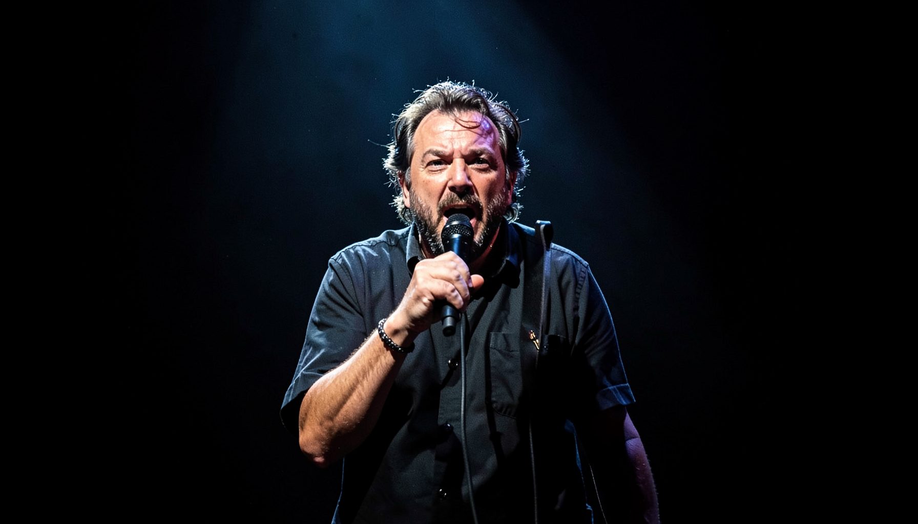 Lead vocalist at center stage, microphone in hand, dramatic spotlight against dark background